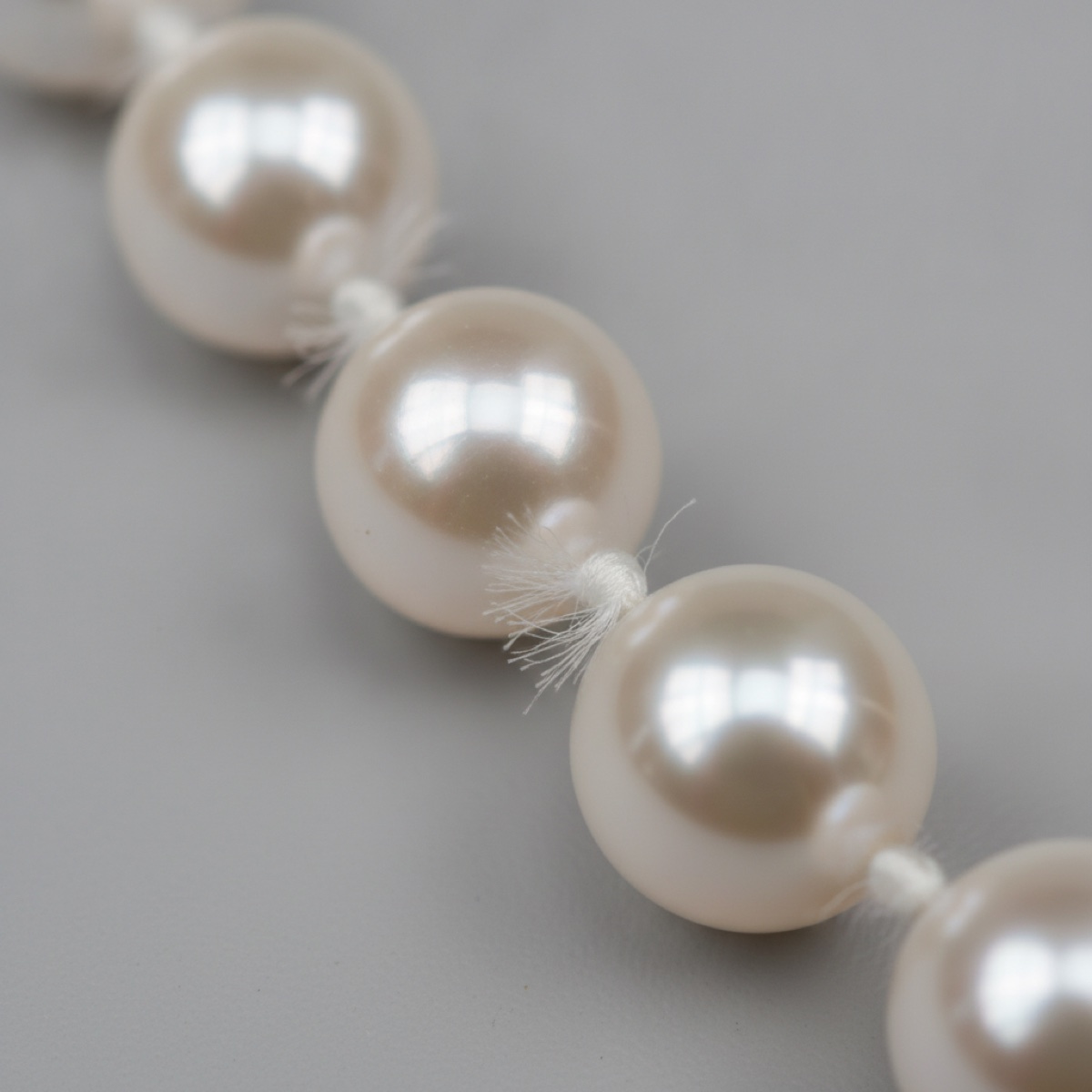 Macro of a knotted South Sea strand, the silk knots and the window reflection visible